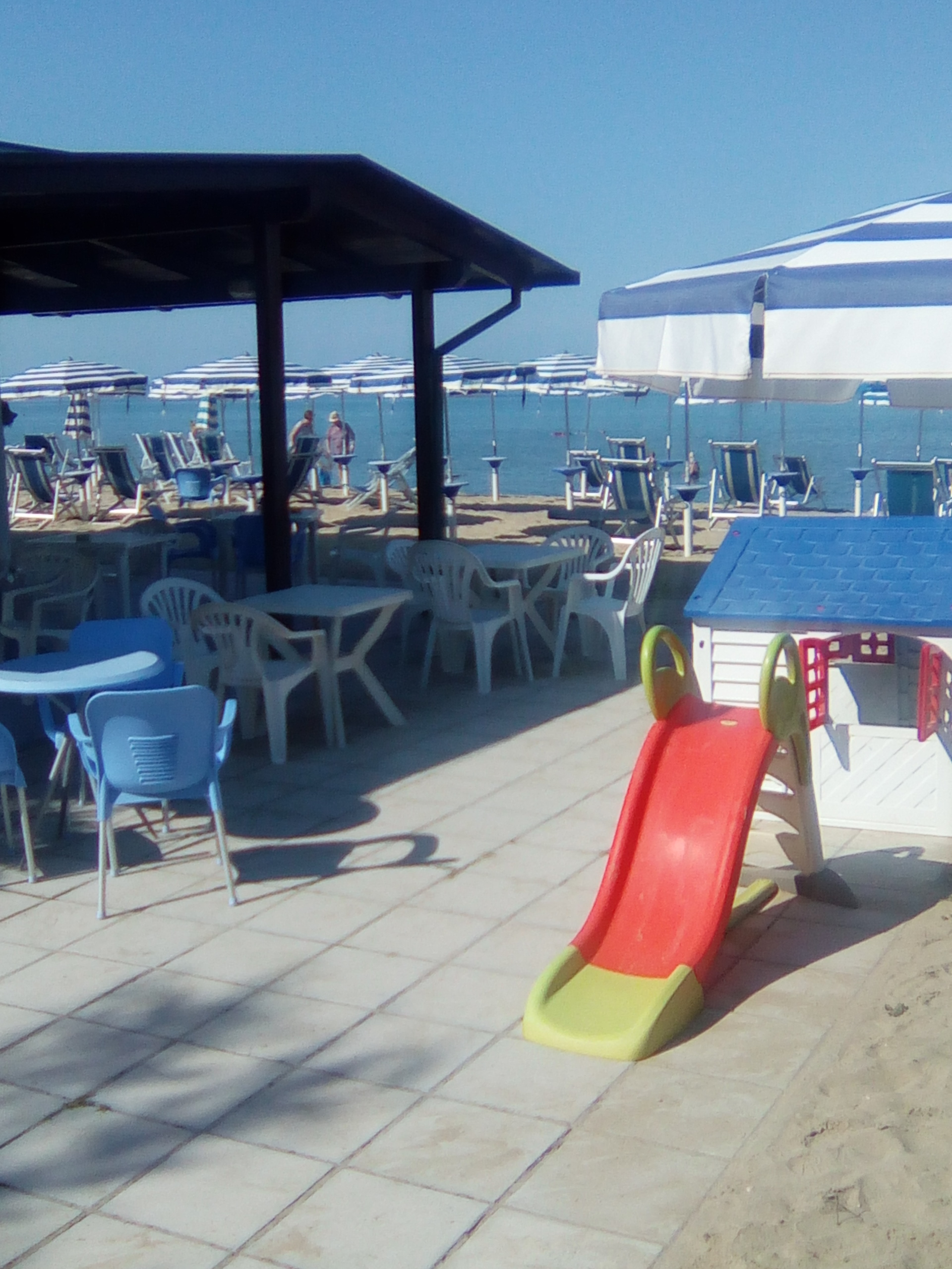 I tavoli del lido all'ombra del gazebo, con lo scivolo per i bambini sulla sabbia