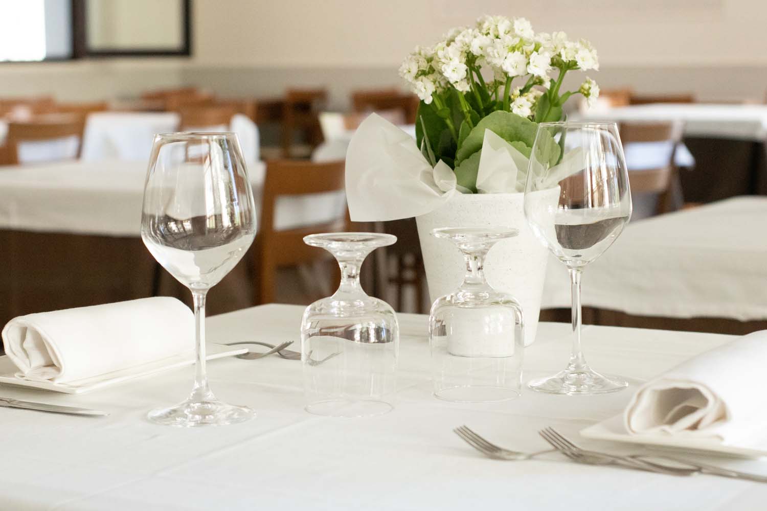 Il tavolo apparecchiato del ristorante con la sala e i tavoli sullo sfondo
